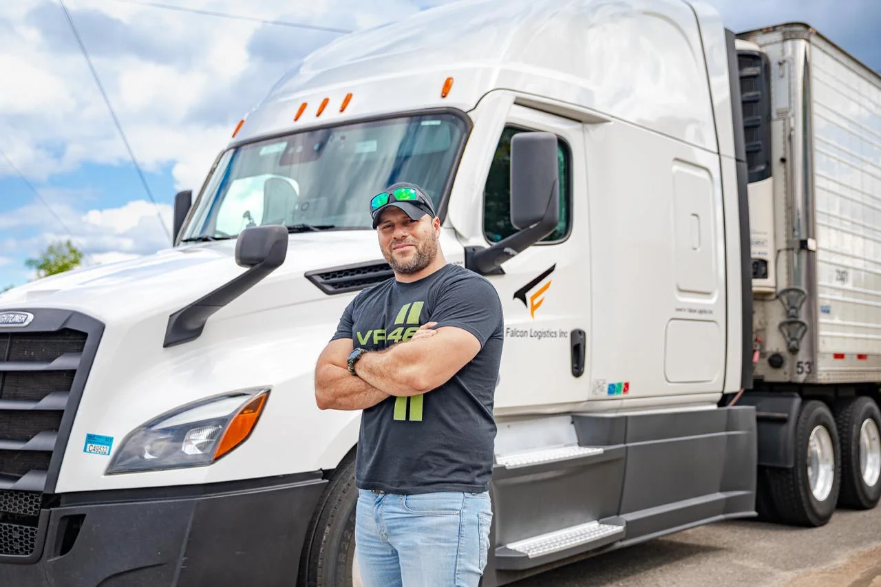 Falcon Logistics Inc driver in front of Freightliner truck